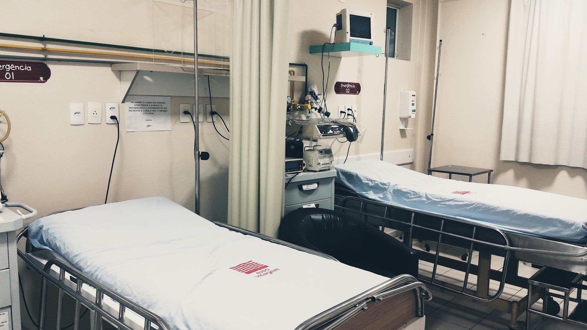 An empty hospital room equipped with two beds, monitoring equipment, and ambient lighting.