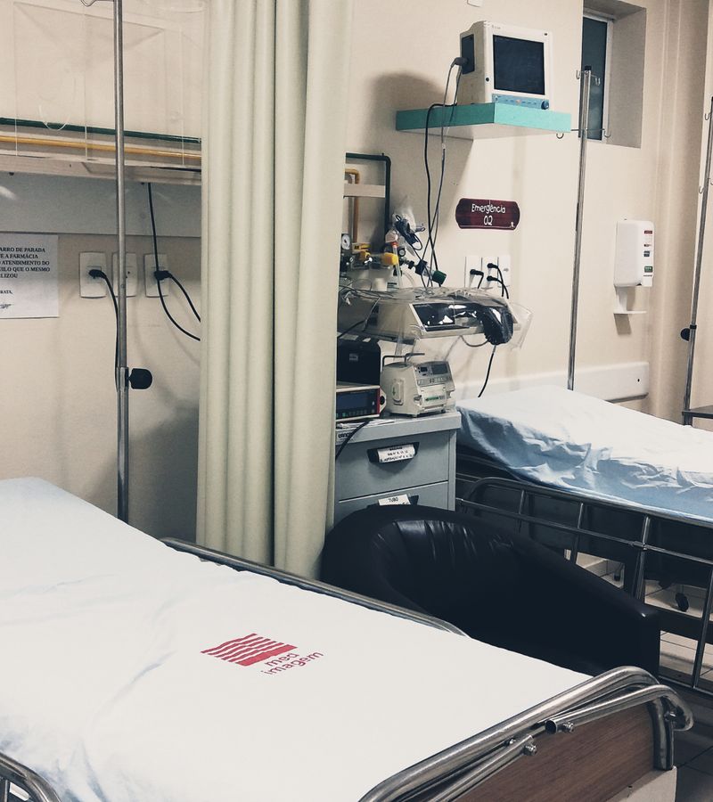 An empty hospital room equipped with two beds, monitoring equipment, and ambient lighting.