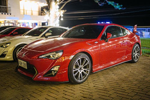 Red Car Parked on Stone Pavement 