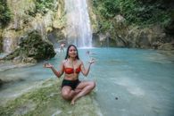 一名女子在风景如画的瀑布旁冥想，尽显大自然的和平与安宁