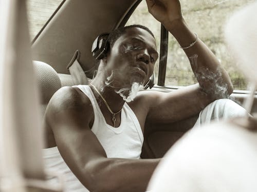 Young Man in Headphones Smoking in Car