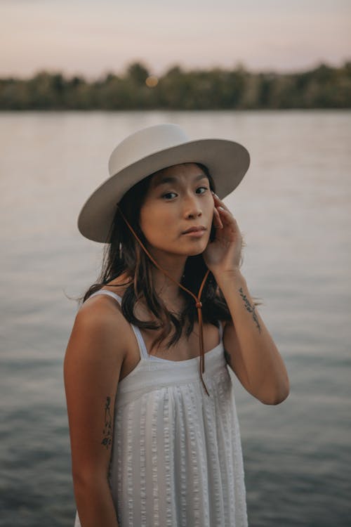 Asian woman in hat standing on lake shore