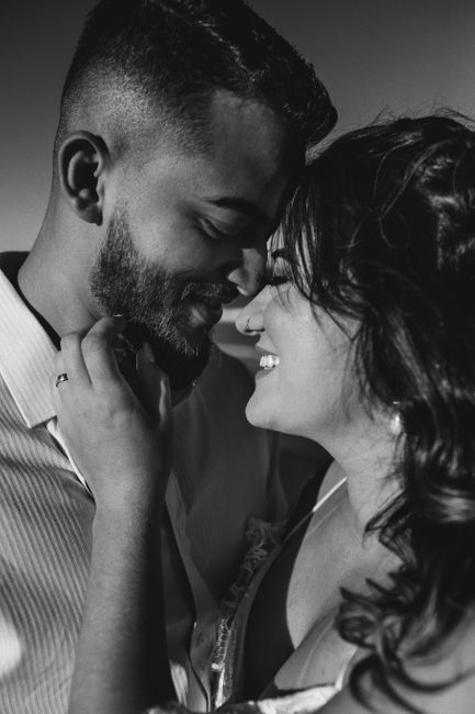 Black and white of happy young ethnic female smiling and touching face of handsome bearded boyfriend