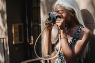 Woman in Black and White Polka Dot Shirt Holding Black Dslr Camera