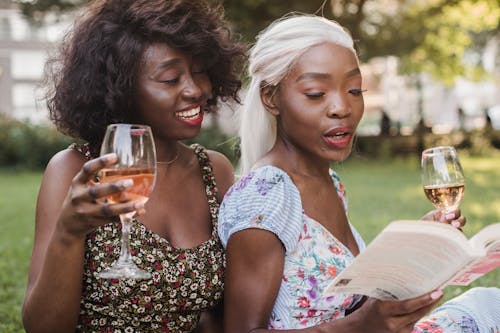 Happy Women Drinking Wine Reading Book on Picnic