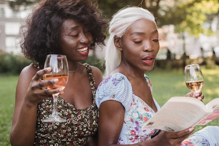 Happy Women Drinking Wine Reading Book On Picnic