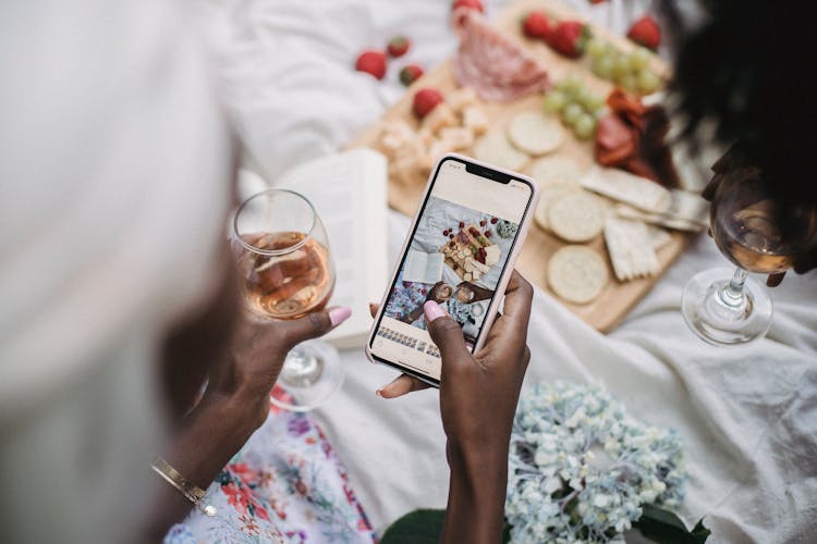 Woman Toking Picture On Cellphone Of Outdoor Picnic