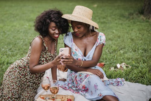 Free Women Sitting on Grass Field Looking at the Phone  Stock Photo