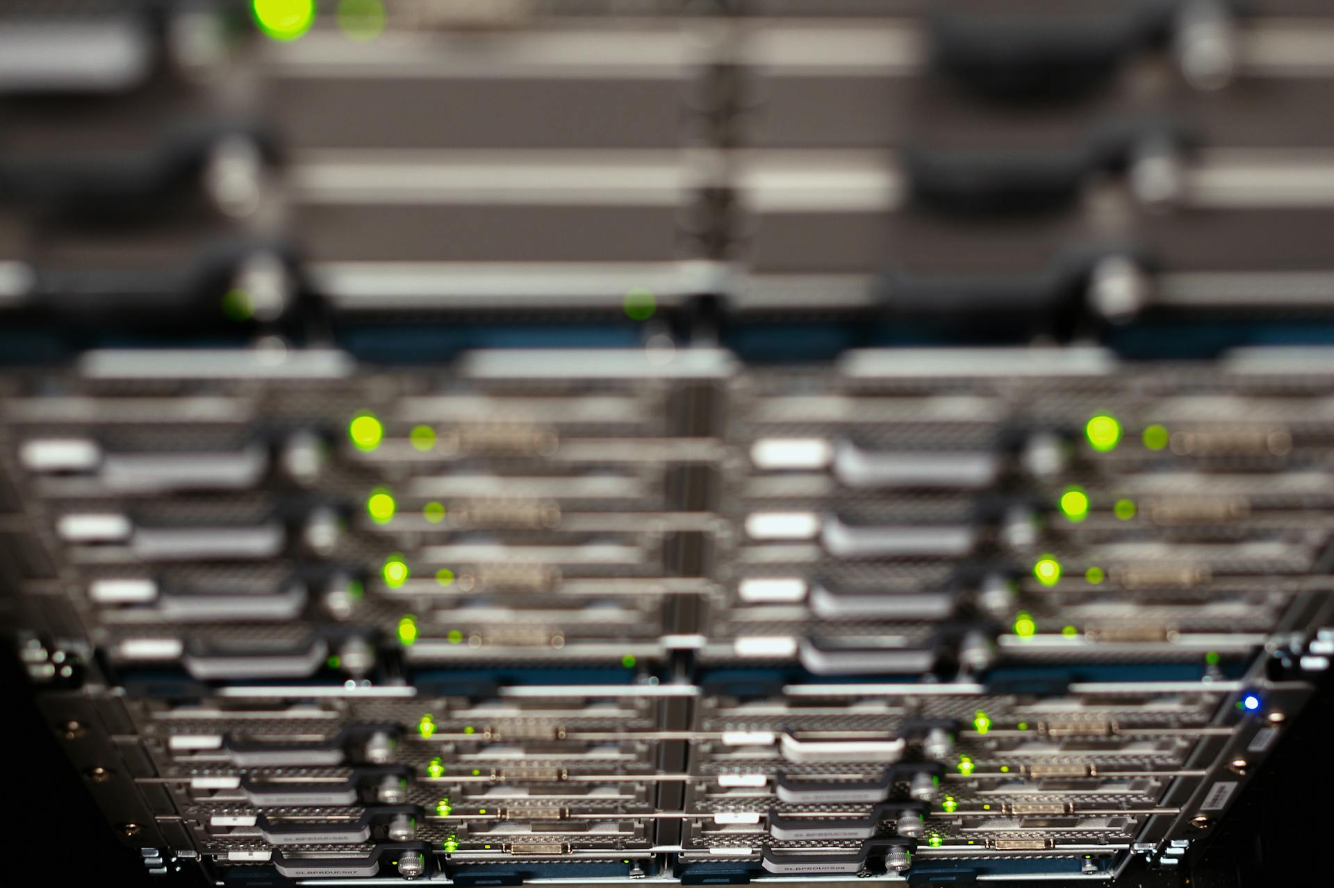 Close-up of a network server rack with blinking LEDs, showcasing Ethernet connections and patch panels.