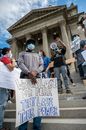 From below group of multiracial activists wearing respirators and holding placards and megaphone while attending rebel meeting near city government building