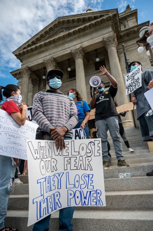 Free From below group of multiracial activists wearing respirators and holding placards and megaphone while attending rebel meeting near city government building Stock Photo