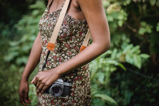 Close-up of a woman carrying a vintage camera in a floral dress outdoors.