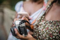 身穿花卉上衣的人手持复古相机，特写镜头营造出经典的氛围