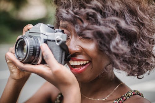 Free Close-up of a Curly Woman Using a Camera to Take Pictures Stock Photo