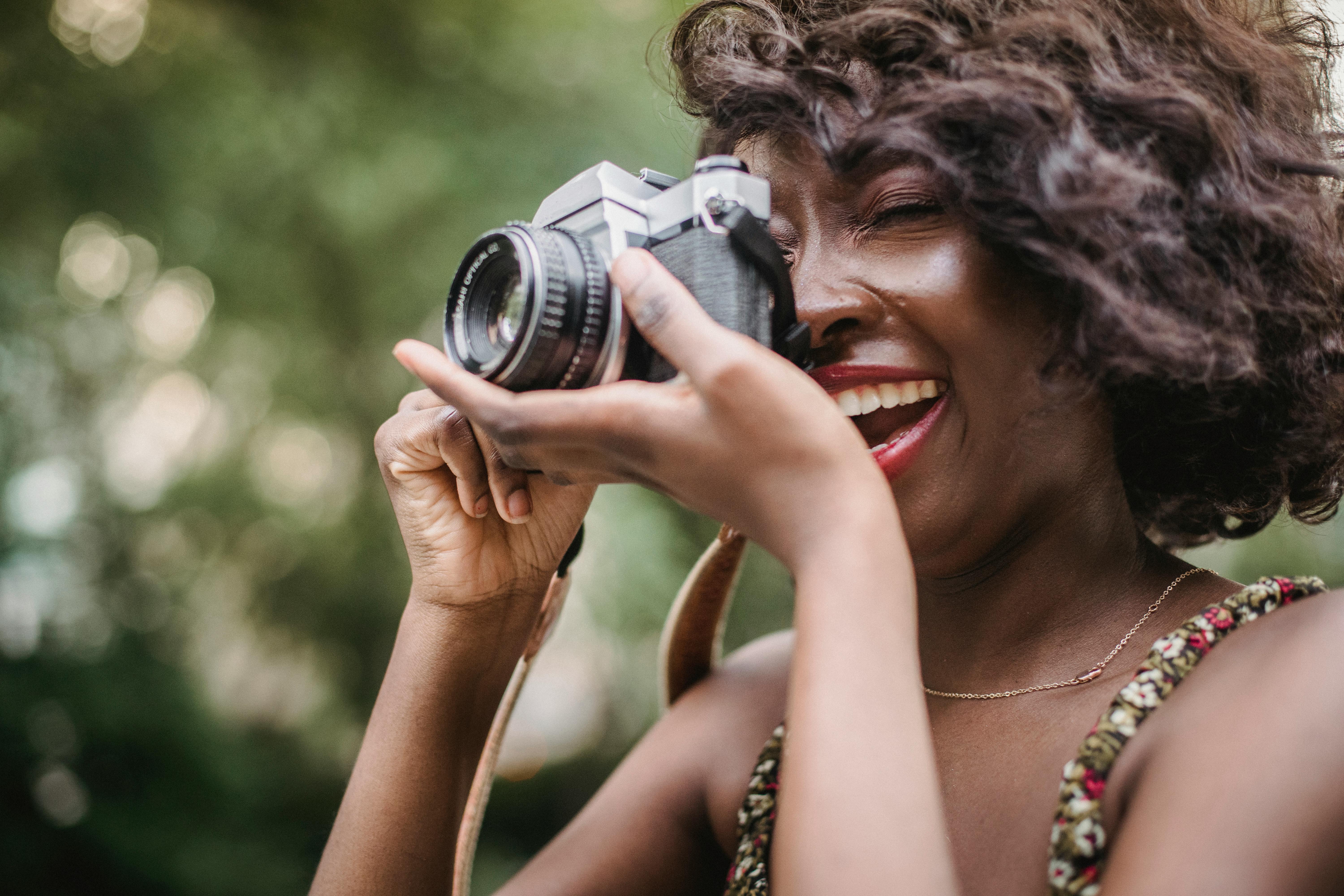 Mujer con gafas de sol tomando fotos con cámara analógica