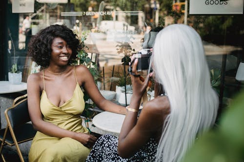 Woman With White Hair Taking Picture of Woman in Yellow Dress