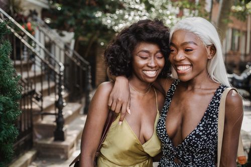 Free Two smiling women embracing outdoors on a sunny day, wearing sleeveless dresses. Stock Photo