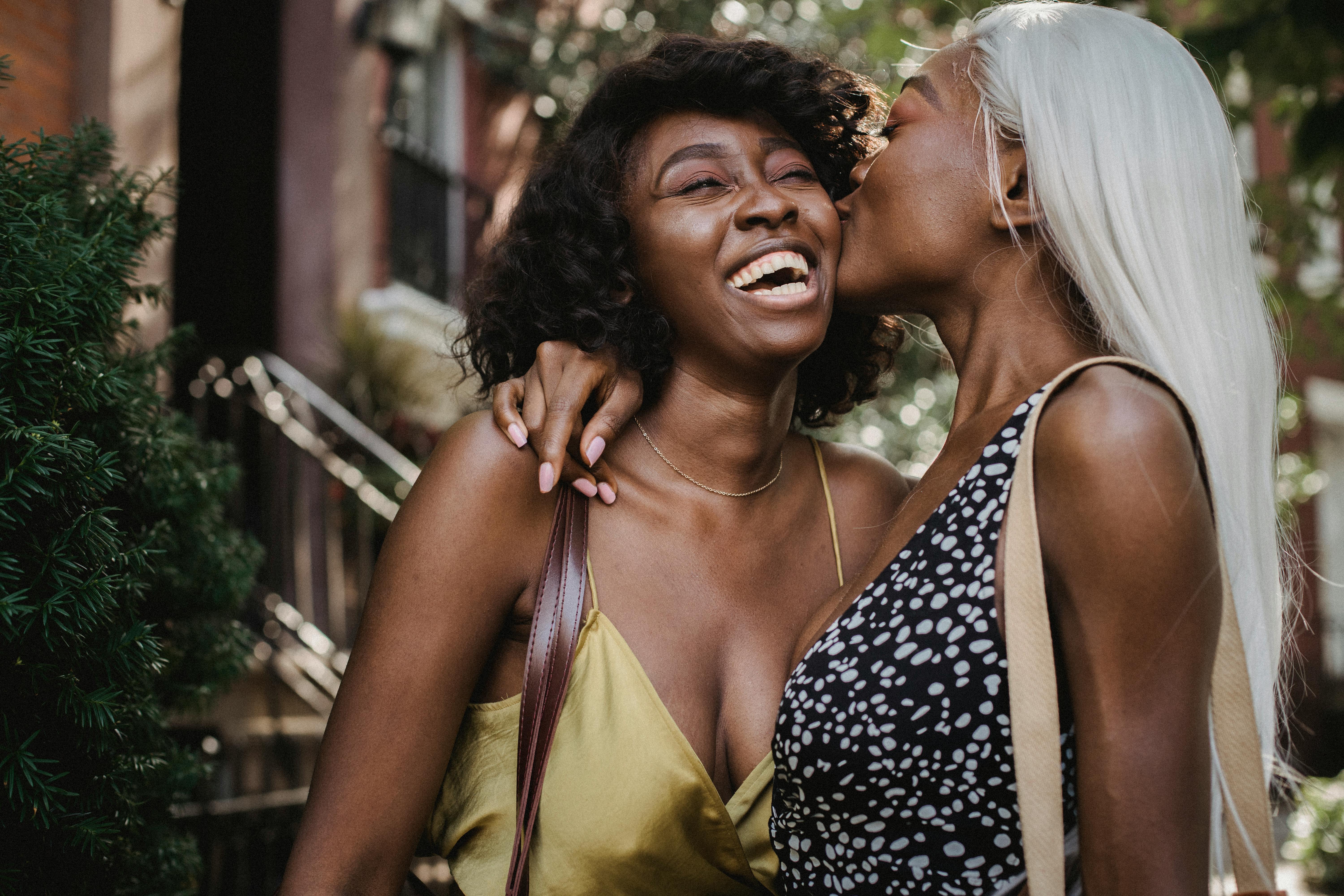 woman in black and white polka dot top kissing her friend