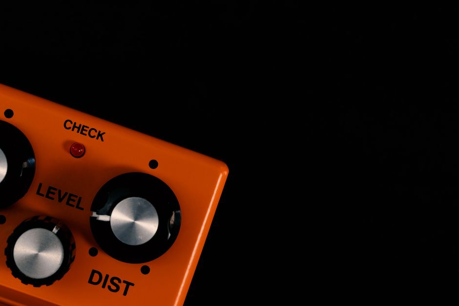 Zdjęcie pedału Lateral Sound Deadblow, efektu distortion o unikalnym designie, leżącego na tle sprzętu muzycznego.