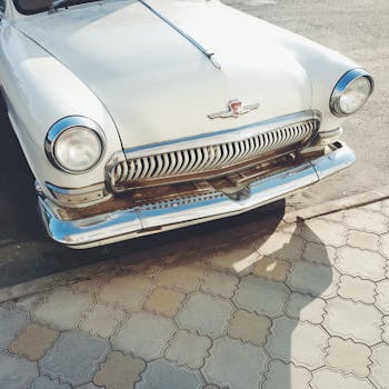 Front view of a vintage classic car with a chrome grille captured in sunlight.