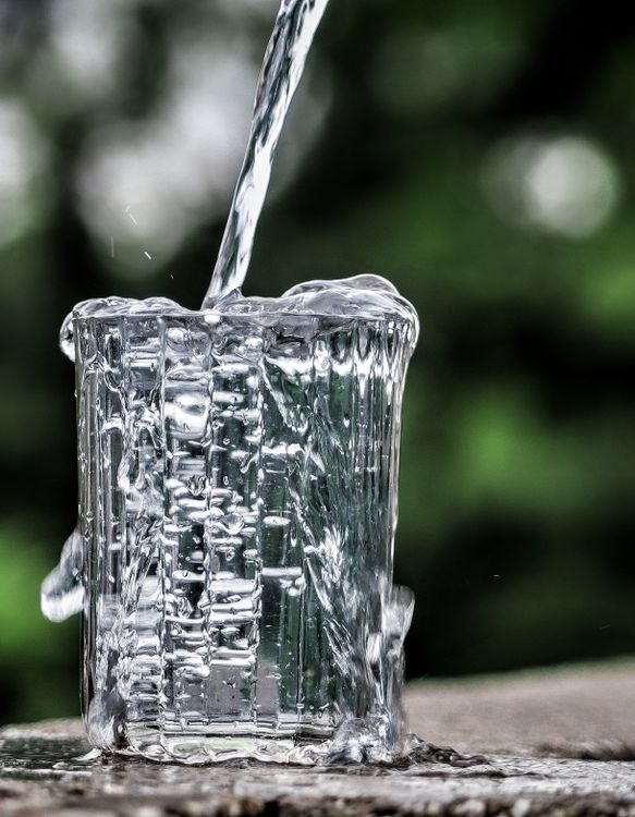 Wasser wird in ein klares Glas gegossen