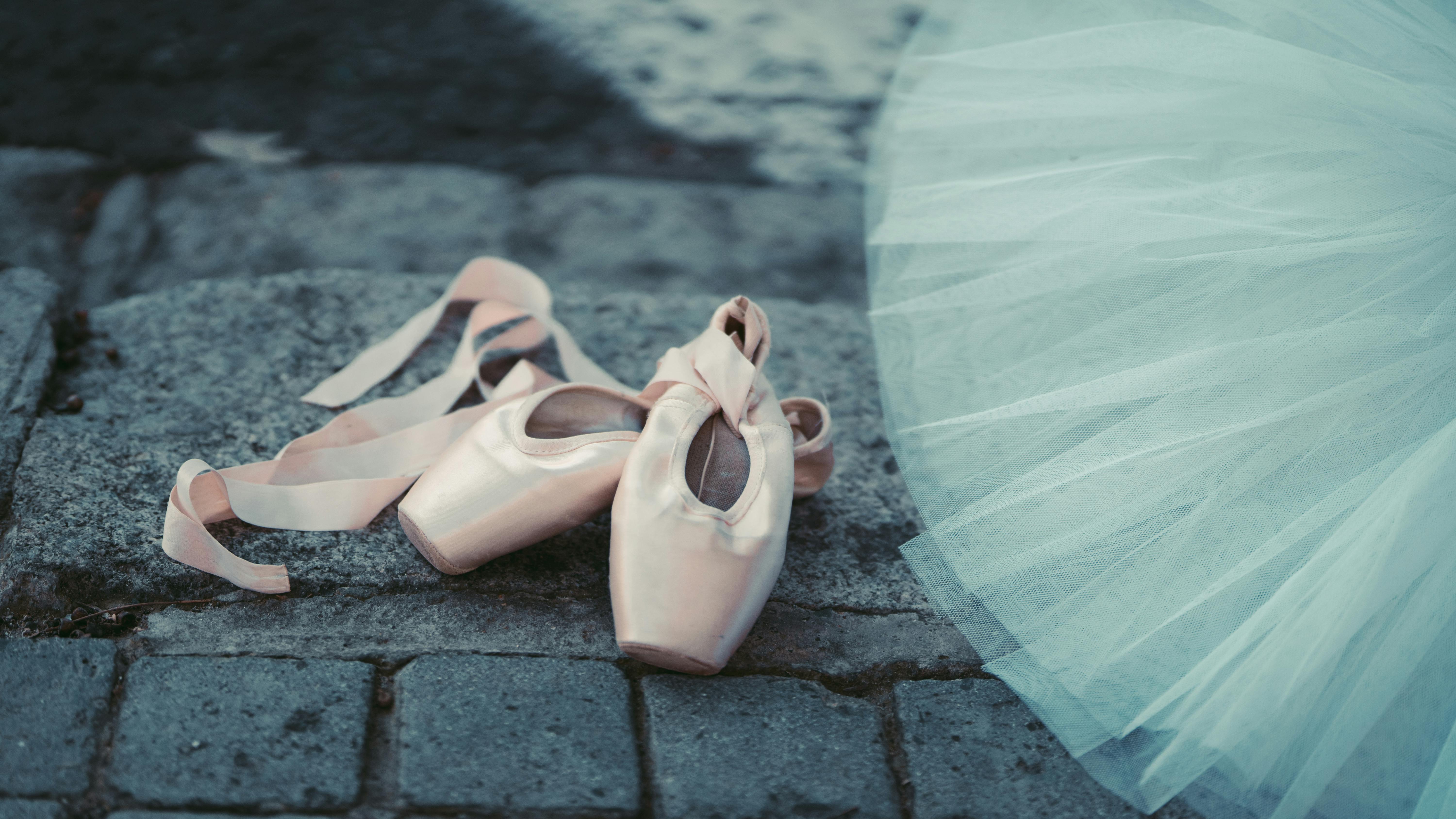 Free Close-up of ballet pointe shoes on cobblestone with a blue tutu, emphasizing elegance and grace. Stock Photo