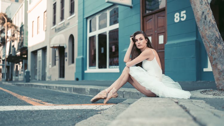 A Ballerina Sitting On A Curb 