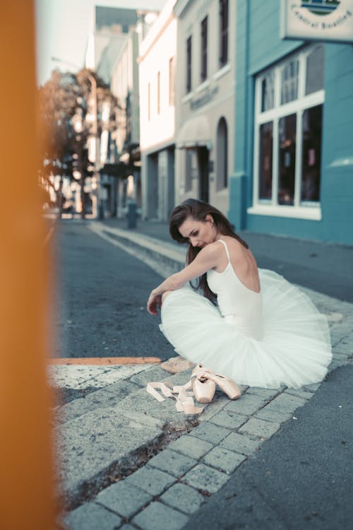 A Female Ballet Dancer Sitting on a Curb