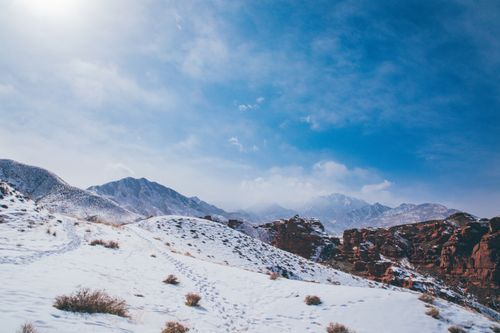 Free From below of bristly mounts with snow and faded grass in mist under blue cloudy sky with glowing sunlight Stock Photo