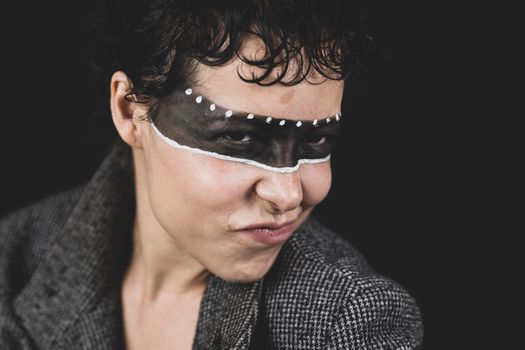 Portrait of a woman with artistic face paint and expressive pose, showcasing creativity and individuality.