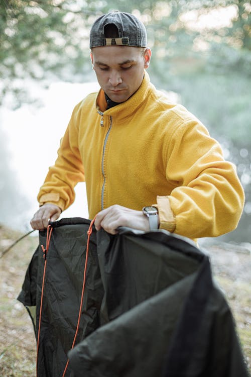 Mann In Der Gelben Reißverschlussjacke, Die Schwarze Lederhandtasche Hält