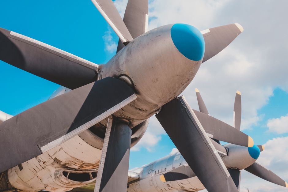 Detailed view of large airplane propellers with blue sky and clouds in the background.