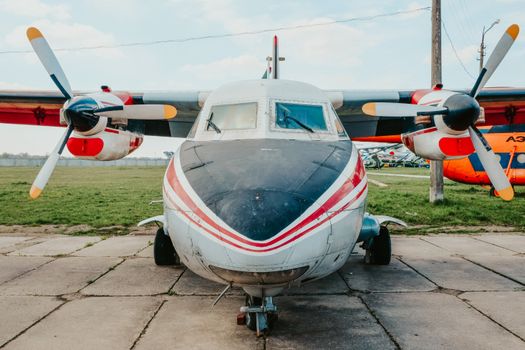 Front view of an old turboprop airplane parked outdoors on a sunny day.