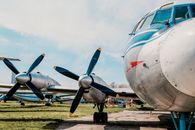 White and Blue Airplane on Brown Field Under White Clouds