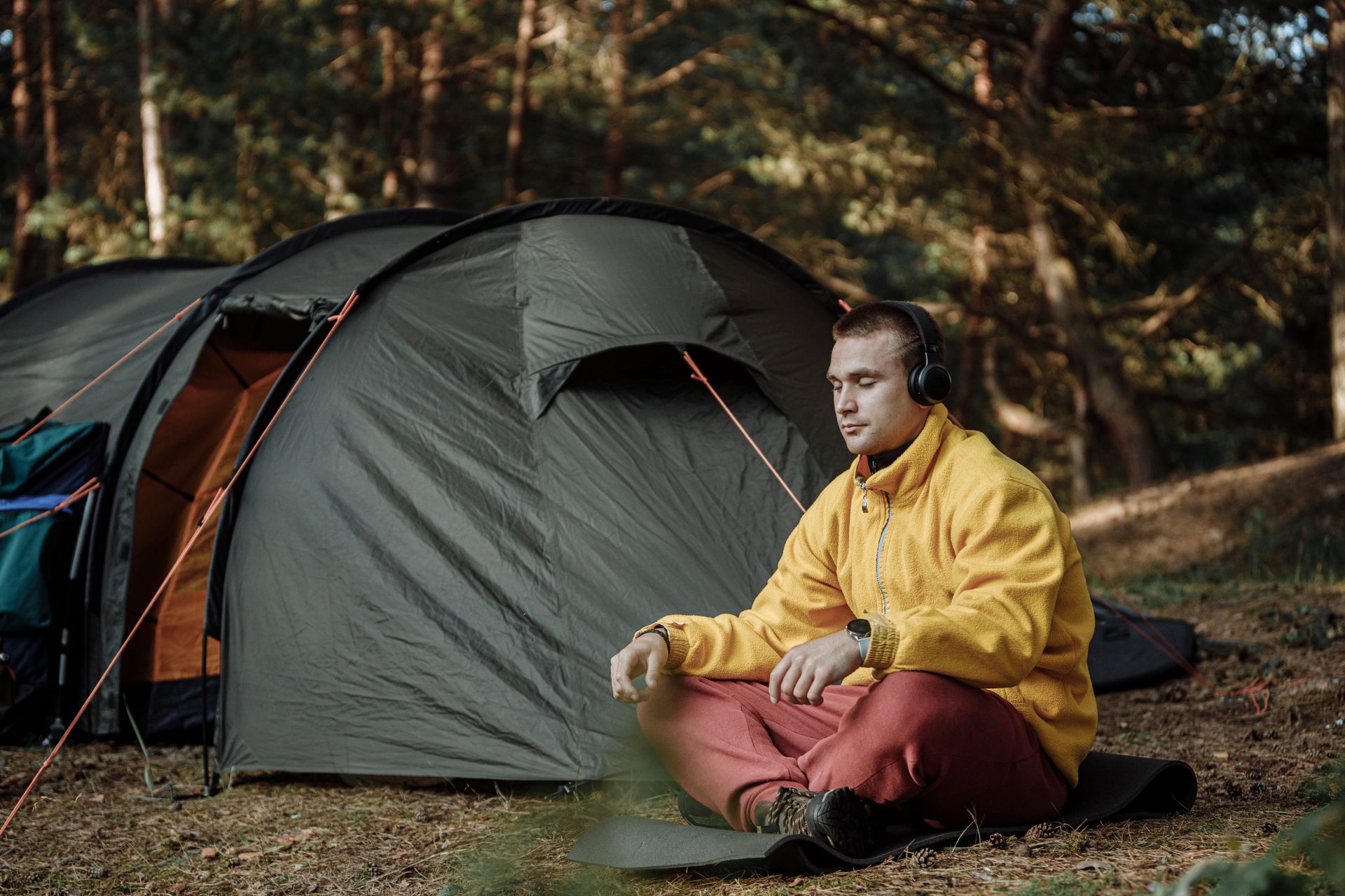 Man in Yellow Jacket Sitting Beside Gray Tent