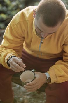 一名穿着黄色夹克的男子在户外拿着一个杯子，正值温暖的秋天