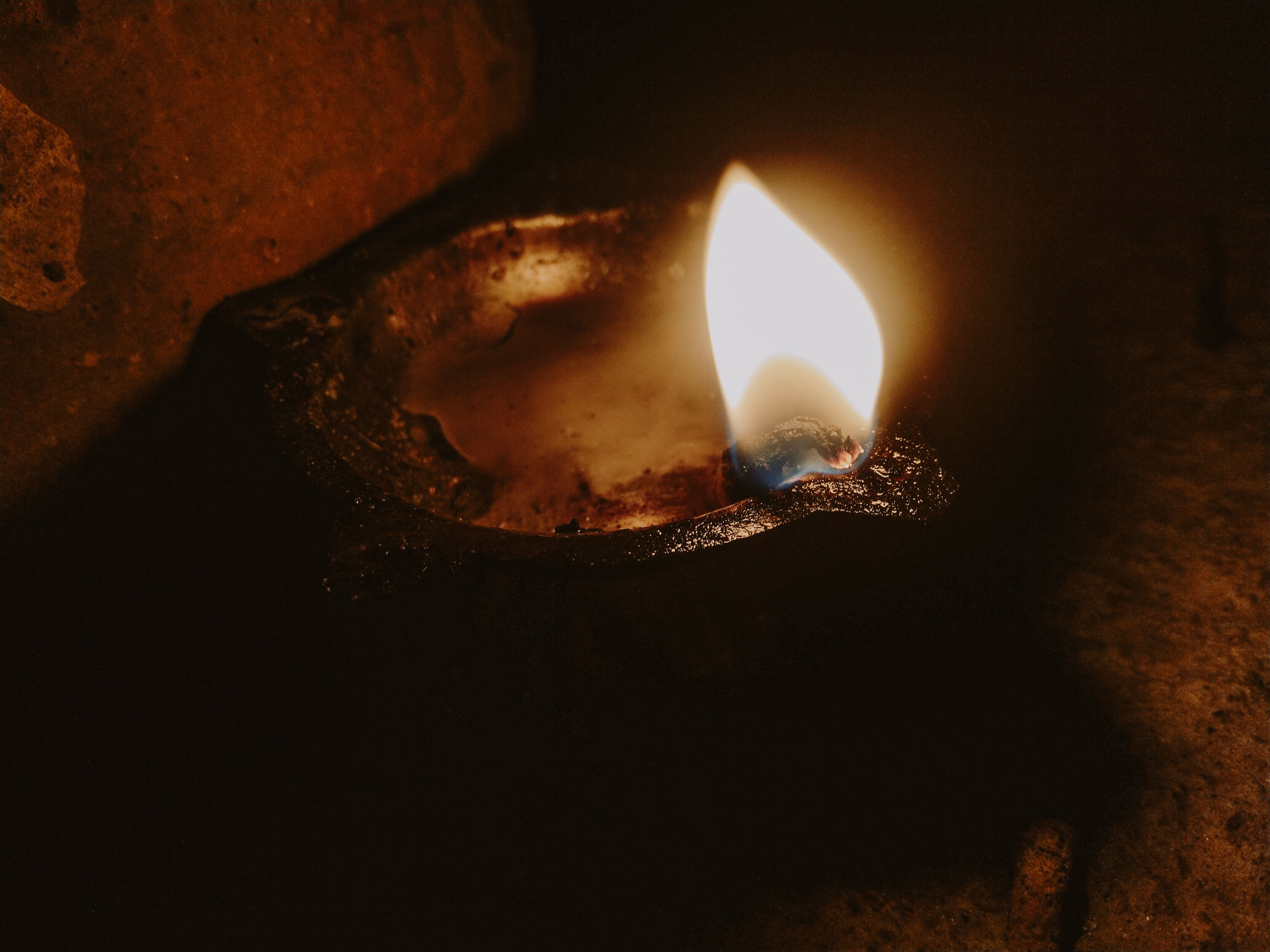 A close-up of a traditional oil lamp emitting a warm glow in a dark setting.
