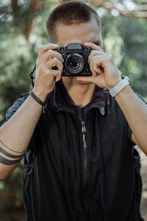 Free Adult male photographer taking a photo outdoors in a natural setting. Stock Photo