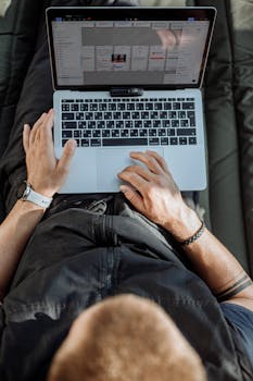 Overhead view of an adult typing on a laptop, symbolizing remote work and digital nomad lifestyle.