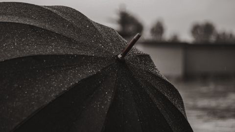 Detailed view of a black umbrella covered in raindrops during rainy weather.