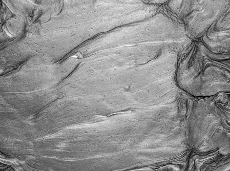 Close-up of abstract silver metallic texture with swirling liquid patterns.