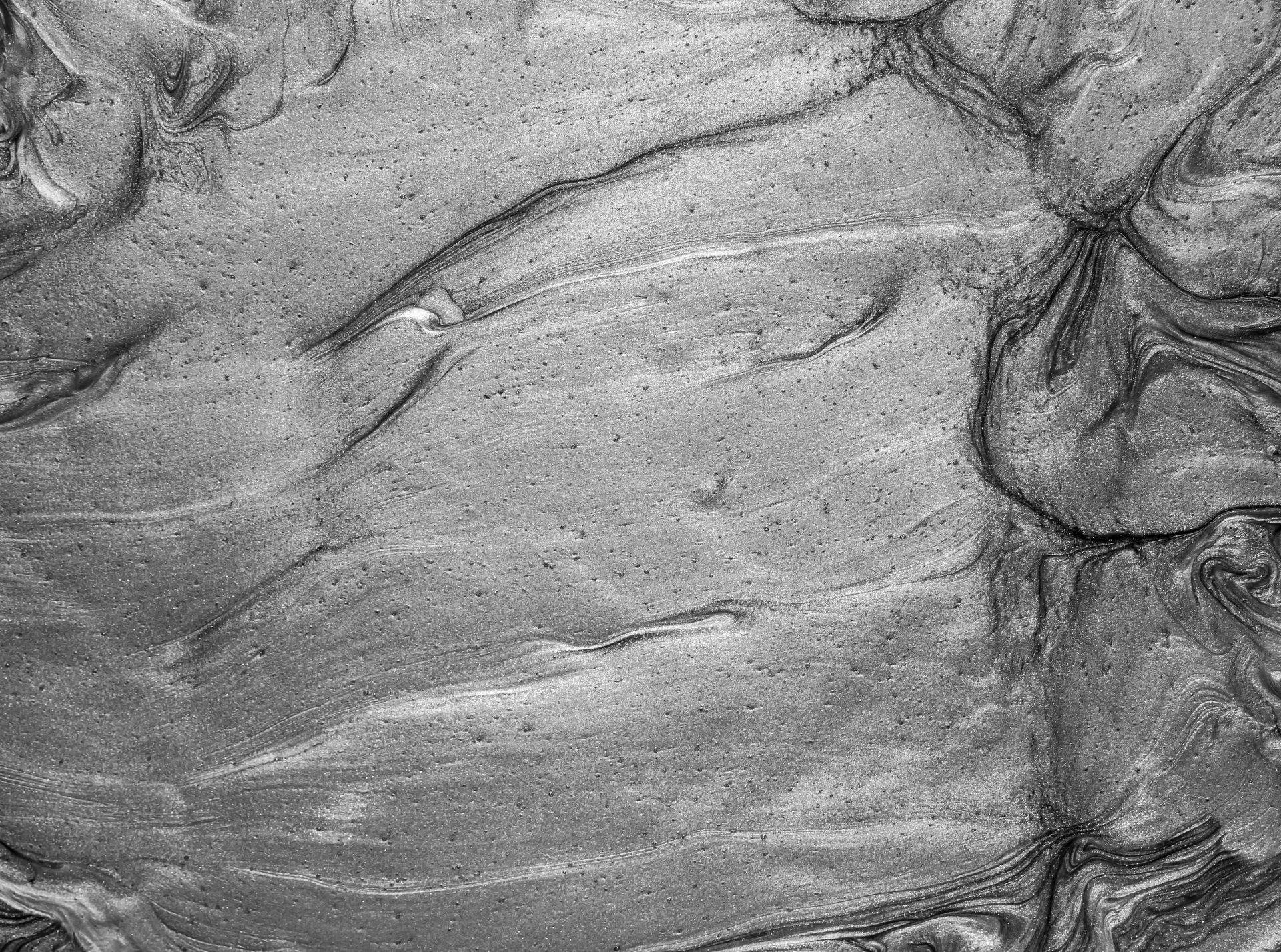 Close-up of abstract silver metallic texture with swirling liquid patterns.