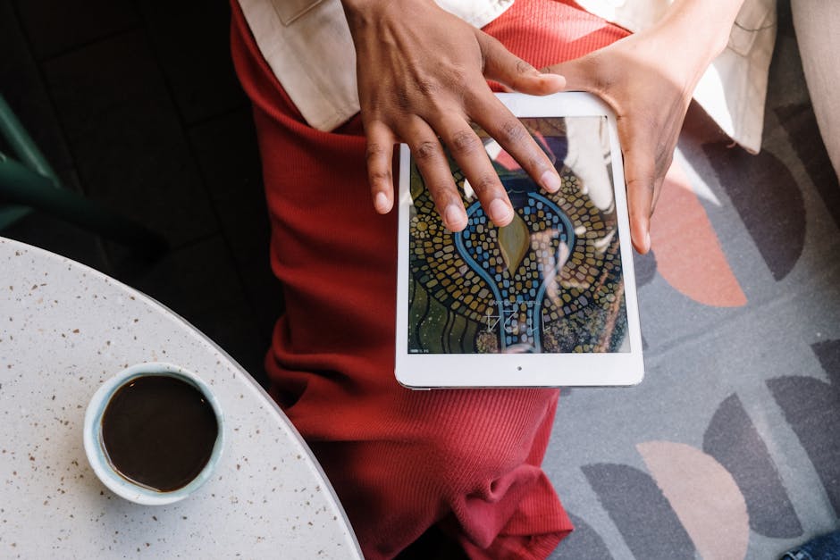 Hand interacting with tablet displaying art in a cozy café setting.