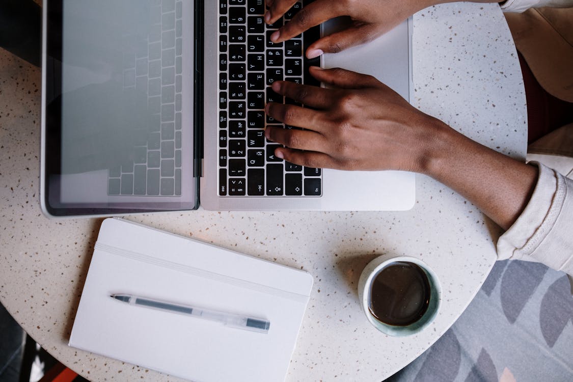 Free Person Using Macbook Pro on White Table Stock Photo