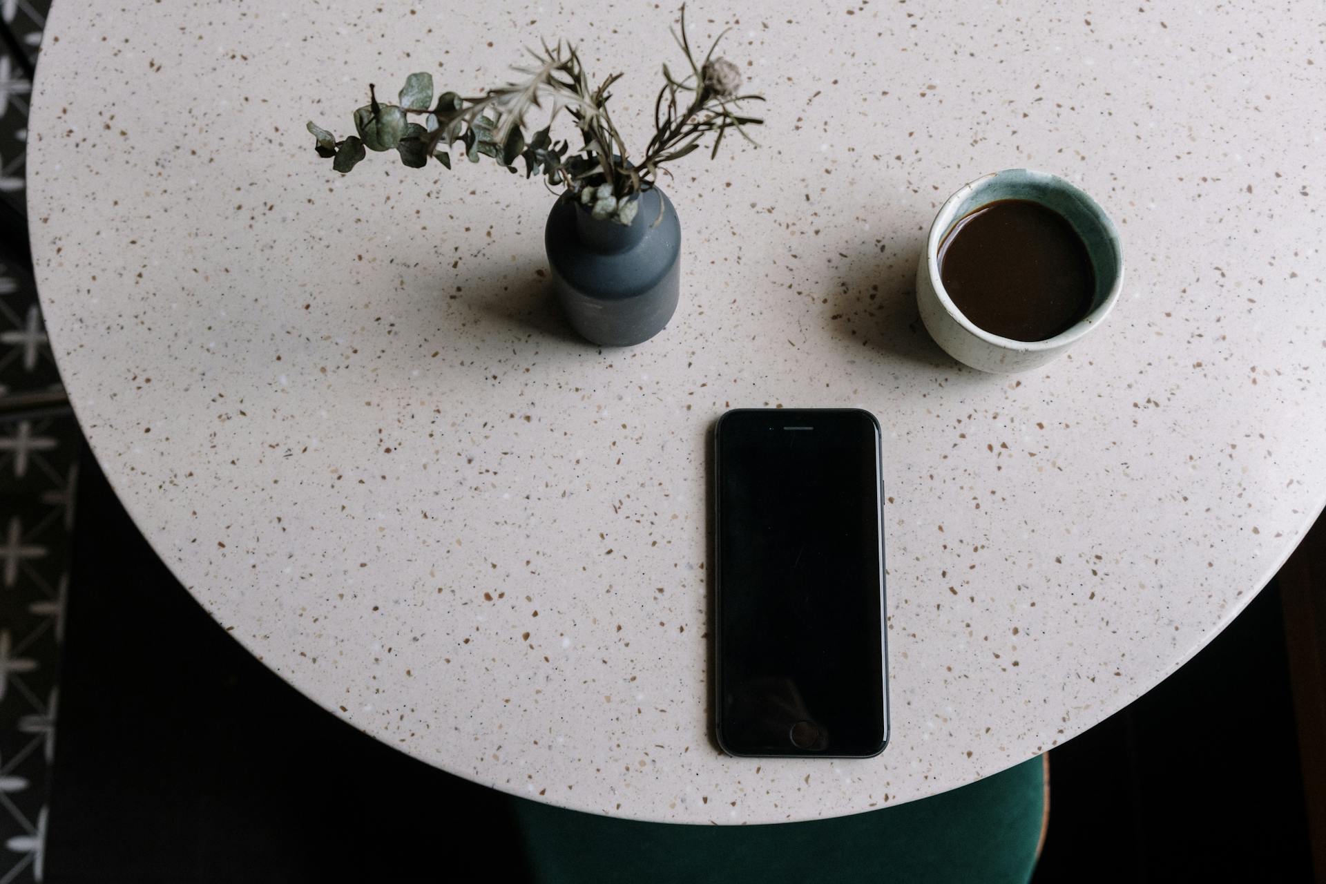 Black Iphone 5 Beside White Ceramic Mug on White Table