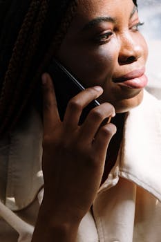 Close-up of a woman using a cellphone, illuminated by sunlight, conveying communication.