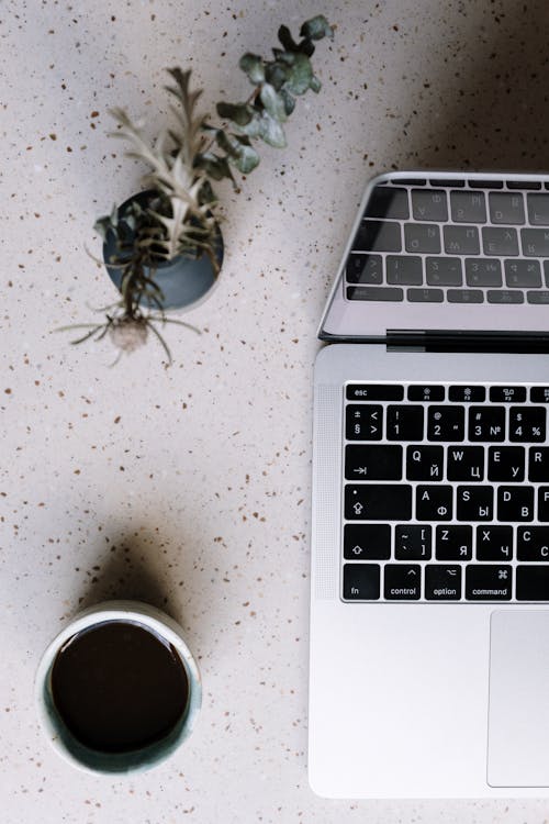 Macbook Pro Beside Silver and Black Cup