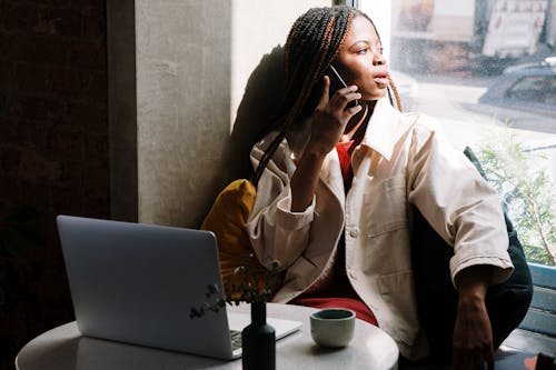 Free Woman in Beige Coat Sitting by the Table With Macbook Stock Photo