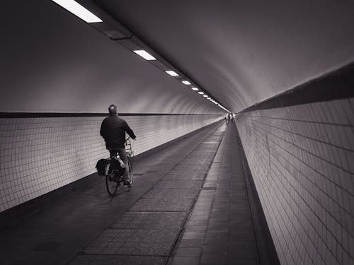 Unrecognizable man riding bike in light tunnel