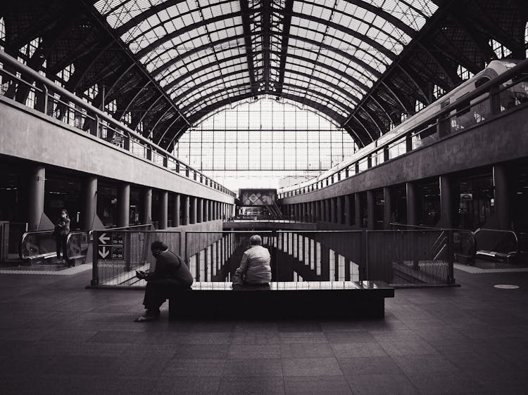 Unrecognizable Travelers On Bench In Railway Station